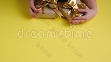 儿童`的手的俯视图在彩色黄色背景上放置各种礼品盒。 圣诞节，新年，生日概念。