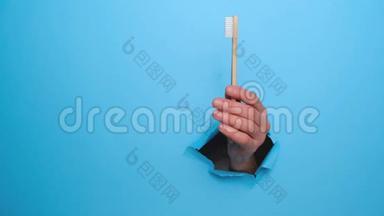 用手<strong>握住</strong>竹子生态牙刷，用手<strong>握住</strong>被撕裂的蓝色纸墙。