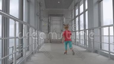 一个小女孩沿着酒店走廊跑到电梯。 全景视窗提供美丽的海景