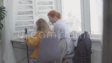 小女孩坐在前台的桌子旁，红头发的妈妈在旁边缝衣服