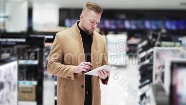 穿棕色外套的年轻帅哥在<strong>化妆品店</strong>里用数码平板电脑