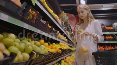 超市里一个漂亮的金发女郎选择橘子，把它们放进一个袋子里<strong>称重</strong>