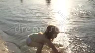 宝宝在水中飞溅.. 泼水。 可爱的孩子在海滩上快乐地玩耍。 快乐的孩子在日落时洗澡