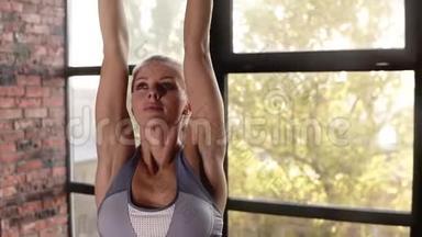 一个漂亮女人做伸展运动的肖像-在室内训练工作室伸展手臂。 健身妇女
