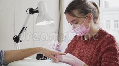 穿粉色面具的女指甲技师在美容院做美甲客户..