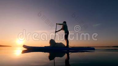 日落时分一位女士和一只狗的站立式划桨