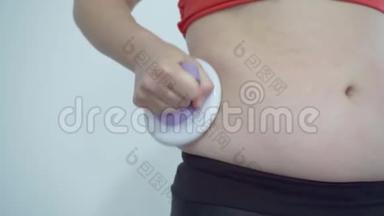 胖女孩做腹部按摩以<strong>摆脱</strong>多余的体重。 含有脂肪的按摩器