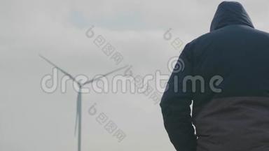 一个职业摄影师在一个<strong>多云</strong>的日子站在一个旋<strong>转</strong>的风力发电机和准备一张照片