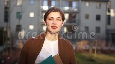 一位年轻的房地产经纪人在一座城市新大楼的院子里的肖像。 幸福女人，房地产，乔迁