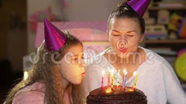 母亲和女儿在聚会上吹灭生日蛋糕上的蜡烛，许愿