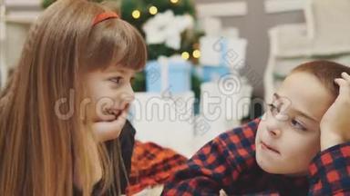 特写4k视频可爱的小朋友一起度过愉快的时光，在圣诞树附近的地毯上交流..