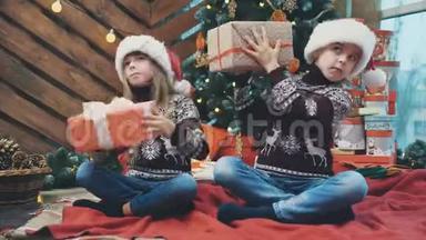 小双胞胎<strong>坐在</strong>圣诞<strong>树下</strong>，摇动礼物盒，倾听并找出里面是什么。