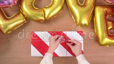 一位穿着白色毛衣的年轻女士正在包装，用金色气球包装漂亮的礼品盒，准备节日准备
