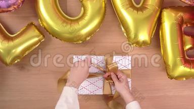 一位穿着白色毛衣的年轻女士正在包装，用金色气球包装漂亮的礼品盒，准备节日准备