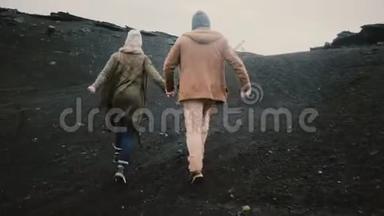 后景年轻夫妇牵着手，穿过黑色的沙子<strong>跑到</strong>海滩，在冰岛著名的景象。