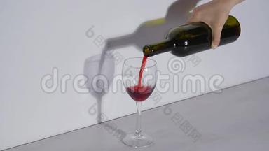 概念镜头，在灰色背景下将红酒倒入玻璃杯中