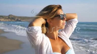 戴着太阳镜的美丽女士微笑着玩着她的头发漫步在海岸边。自由女神像