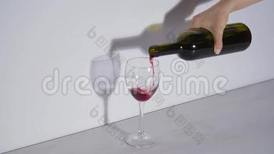 概念镜头，在灰色背景下将红酒倒入玻璃杯中