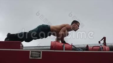 强壮的男人在消防车上做俯卧撑。 近景