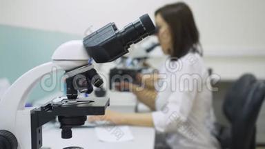 细胞学实验室。 实验室里穿着实验室外套的医务人员背景上的显微镜。