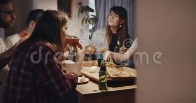 年轻的多民族快乐的男女朋友吃披萨和饮料，在家庭厨房聚会上聊天慢动作。