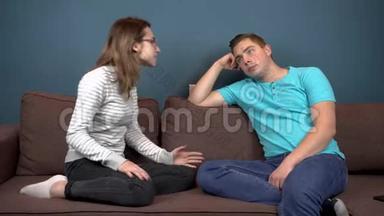 一个年轻的女人对一个年轻人大喊大叫。 男人不注意女人。 坐在沙发上