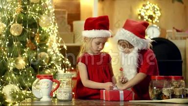 两个戴着圣诞帽的<strong>快乐</strong>可爱的孩子带着礼物<strong>过</strong>圣诞节。 新年圣诞节的概念。 <strong>快乐</strong>的孩子抱着