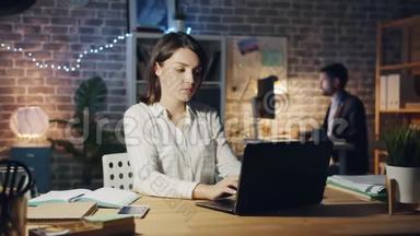 精疲力竭的女士用笔记本电脑打字，然后晚上躺在办公室工作的椅子上