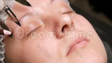 美容师`他的手在病人的脸上用特殊的工具做了一个新形状的眉毛`