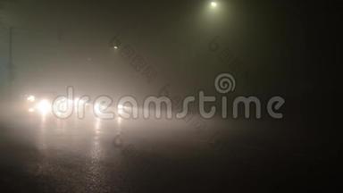 汽车在雾蒙蒙的道路上，夜间能见度差。 汽车和卡车在浓雾中在城市的街道上。 困难和极端的博士