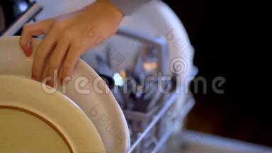 洗碗机。 厨房里做家务的年轻女人。 关闭视野。 洗干净。