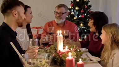 圣诞快乐。 幸福的一家人正在家里吃晚饭。 庆祝节日和相聚在树旁。