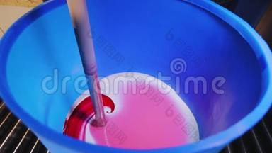 在桶里混合油漆，在工厂里混合油漆，在工厂里混合粉红色油漆