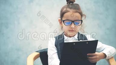 一个女学生`<strong>商务</strong>女孩仔细阅读一个黑色文件夹。 用铅笔黄读。 坐着的女孩是<strong>灰色</strong>的