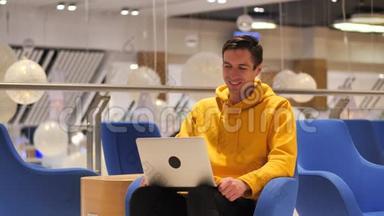 微笑的年轻人在一家现代化的大咖啡馆里用笔记本电脑工作