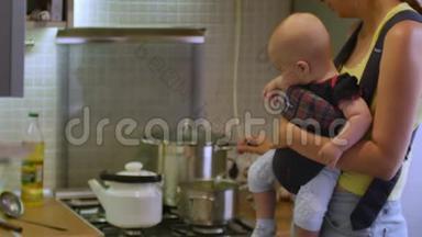 漂亮的女人和一个婴儿坐在婴儿车里<strong>煮汤</strong>在厨房吃晚饭。 母亲家庭