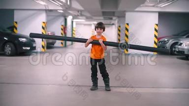 一个手里拿着一根长管子的男孩站在一个停车库里。
