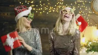 圣诞节快乐有趣的女人戴着带礼品盒的眼镜。 圣诞前夜。 两个脸上洋溢着幸福的女孩迎接新年