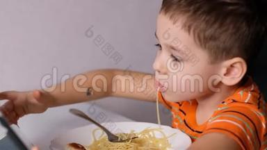 孩子们在餐桌上玩意大利面。 糟糕的脸吃东西。 酱汁和孩子。 男孩坐在托儿所吃面条