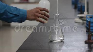 将塑料洗瓶机中的化学液体倒入化学黑色花岗石板上的锥形烧瓶中