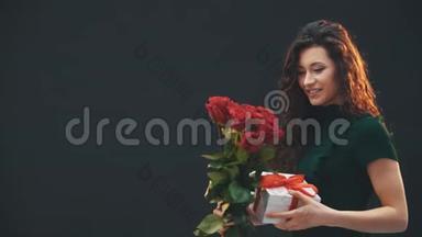 美丽的卷发黑发女孩站着，欣赏着红色条纹和白色盒子<strong>绑</strong>在一起的红色玫瑰<strong>花</strong>束。