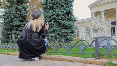 一位戴着帽子的年轻白种人女士用复古相机拍摄纪念碑和建筑的照片