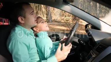 一个人转动汽车的车轮，把他的儿子放在膝上。 快乐的父亲和他的孩子一起坐车旅行