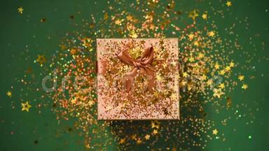 闪闪发光的金色星星，绿色背景上的礼品盒上闪闪发光的纸屑。 上景。 圣诞节和新年的质地
