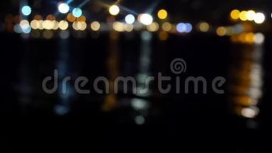 色彩斑斓的离焦海滨城市的夜灯闪烁和挥动的倒影。