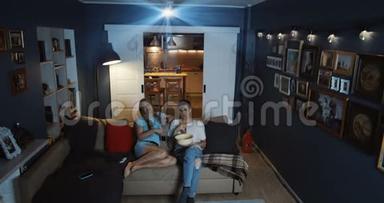 快乐的白种人年轻夫妇在家看<strong>电视</strong>，使用投影仪和<strong>大屏</strong>幕，网络在线电影慢动作。