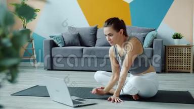 年轻女子正在做瑜伽，看教程，用笔记本电脑在公寓的垫子上