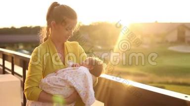 一组视频：穿着黄色上衣的女人用粉红色毯子把她的小婴儿轻轻地抚摸起来