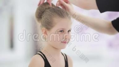 年轻的舞蹈老师给她的学生固定发型