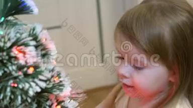 儿童装饰圣诞树. 特写镜头。 婴儿在圣诞树附近玩耍，微笑着。 小女孩